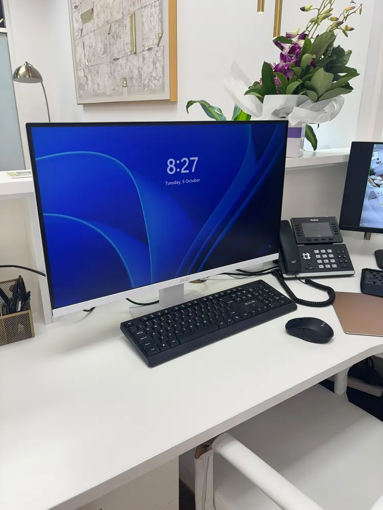 Computer monitor, keyboard, mouse and desk phone set up on a desk