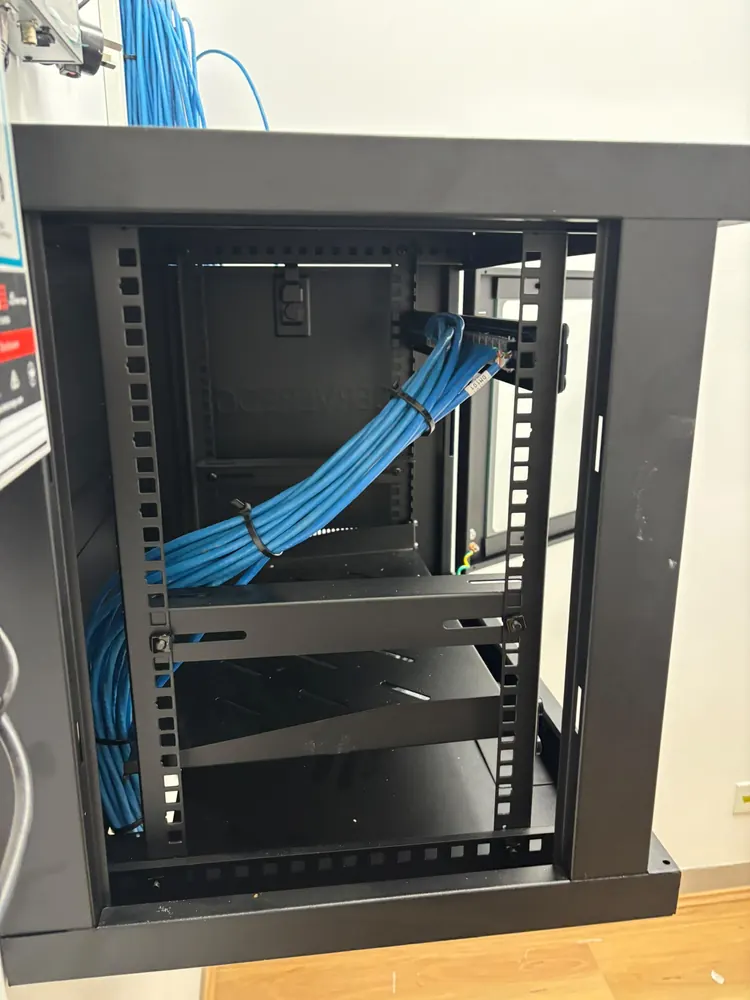 Wall-mount data cabinet with blue Cat6 cables bundled with cable ties and routed up to the patch panel